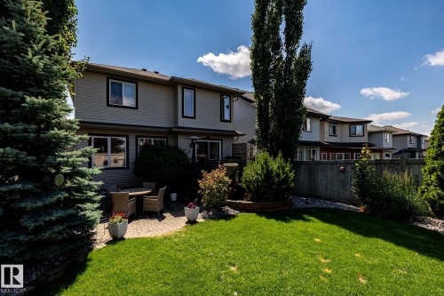Manicured backyard featuring a paver patio, a lush lawn, mature trees, and privacy fencing - 5820 7 Avenue Sw, Edmonton, AB - Outdoor