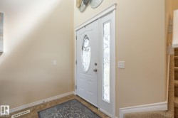 Entryway featuring a white door with an oval-shaped decorative glass insert, a full-length sidelight with patterned glass, tile flooring, and neutral wall tones - 