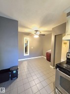 Kitchen area featuring stainless steel range, light-toned tiled flooring, white ceiling fan with integrated lighting, and neutral wall tones - 