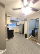 Functional kitchen featuring white cabinetry, a stainless steel refrigerator, and an integrated range hood - 