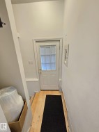 White paneled door with divided lite window, light wood-finish flooring, and white baseboards - 