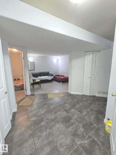 Spacious room featuring gray tile flooring and white baseboards - 9616 63 Avenue, Edmonton, AB 