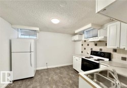 Functional kitchen space featuring white cabinetry, a dual basin stainless steel sink, tile backsplash, and an electric stove with range hood - 