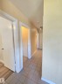 Hallway featuring light-toned tile flooring, light-colored walls, white trim, and a ceiling-mounted light fixture - 9616 63 Avenue, Edmonton, AB 