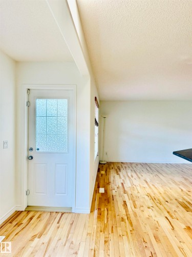 Entryway featuring a solid white door with frosted glass paneling, durable wood flooring, and white baseboards - 3120 25 Avenue, Edmonton, AB 