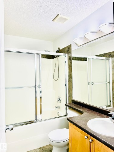 Bathroom featuring a white tub with sliding glass doors, a shower head, and a chrome faucet - 3120 25 Avenue, Edmonton, AB 