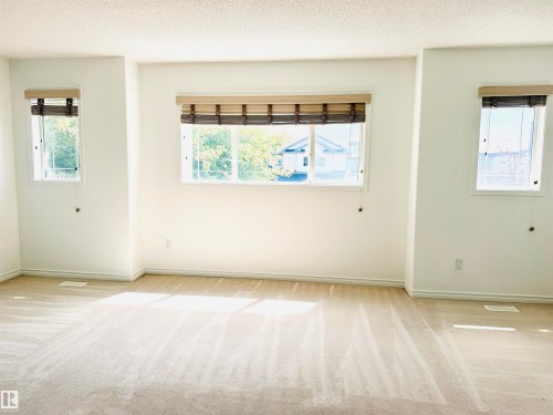 Bright interior space featuring neutral carpeting, white painted walls, and textured window treatments - 3120 25 Avenue, Edmonton, AB 