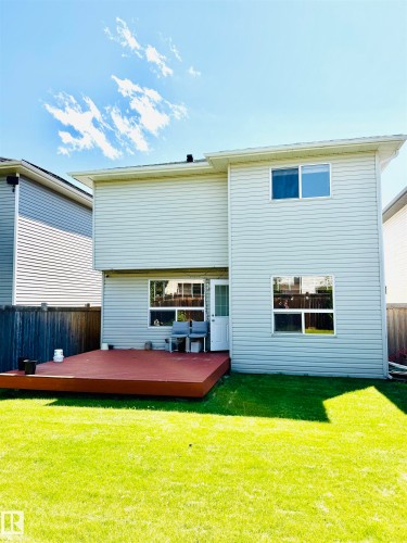 Expansive backyard featuring a manicured lawn, full privacy fencing, and a ground-level wood deck - 3120 25 Avenue, Edmonton, AB 
