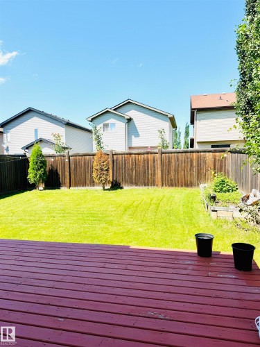 Expansive backyard featuring a red-stained wood deck and a manicured lawn - 3120 25 Avenue, Edmonton, AB 