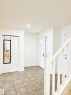 Entryway featuring tile flooring, a white front door with decorative glass, and a white baluster staircase - 3120 25 Avenue, Edmonton, AB 