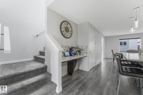 Built-in desk area with a tile backsplash, featuring wood-finish flooring extending into the kitchen and dining areas - 17724 58 Street Nw, Edmonton, AB 