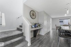 Built-in desk area with a tile backsplash, featuring wood-finish flooring extending into the kitchen and dining areas - 