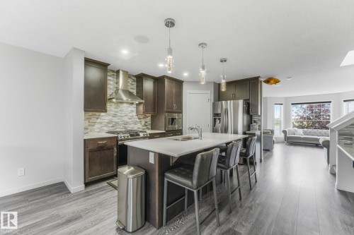 Modern kitchen featuring dark wood cabinetry, stainless steel appliances, and a tiled backsplash - 17724 58 Street Nw, Edmonton, AB 