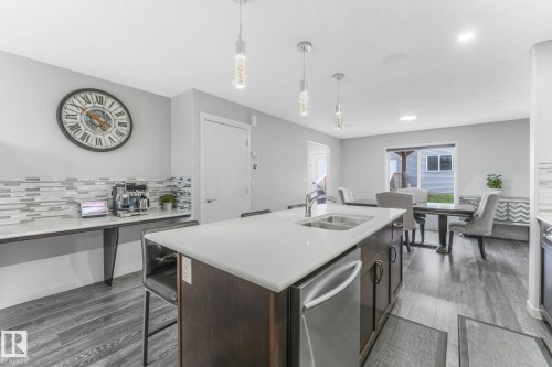 Open concept kitchen and dining area featuring a central island with an undermount double sink, stainless steel dishwasher, and pendant lighting - 17724 58 Street Nw, Edmonton, AB 