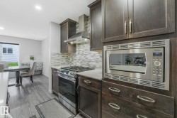 Kitchen featuring dark wood cabinetry, stainless steel appliances, light countertops, and a tiled backsplash - 