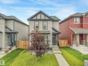 Two-story residence featuring light-colored siding, dark trim accents, and a front entry with stone veneer - 17724 58 Street Nw, Edmonton, AB 