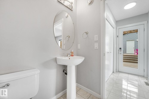Pedestal sink with an oval mirror and light fixture - 17724 58 Street Nw, Edmonton, AB 