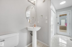 Pedestal sink with an oval mirror and light fixture - 