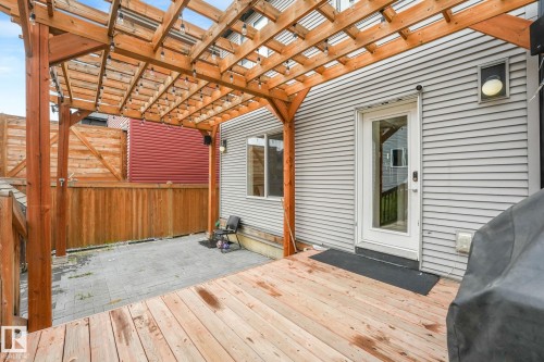 Outdoor deck featuring natural wood planks, a wooden pergola structure, and a glass-paneled exterior door - 17724 58 Street Nw, Edmonton, AB 