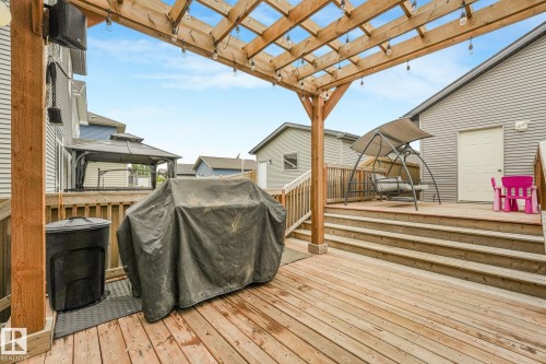 Multi-level wood deck featuring a pergola with string lights, wood railings, and stairs - 17724 58 Street Nw, Edmonton, AB 