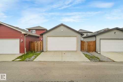 Detached garage featuring light gray siding, a white garage door, and a concrete driveway - 17724 58 Street Nw, Edmonton, AB 