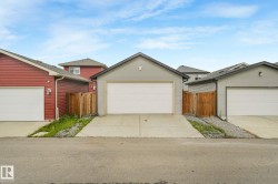 Detached garage featuring light gray siding, a white garage door, and a concrete driveway - 