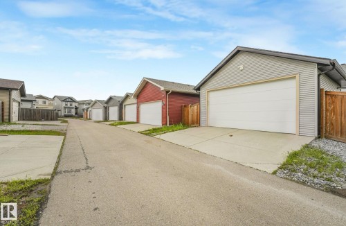 Detached garage featuring light gray horizontal siding, a white garage door, and a dark shingle roof - 17724 58 Street Nw, Edmonton, AB 