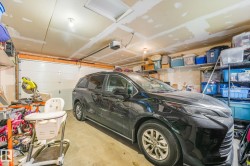 Attached garage featuring a sectional overhead door, exposed ceiling joists, and concrete flooring - 