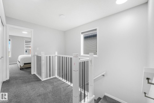 Carpeted landing featuring a white and black spindle railing, natural light from a window, and recessed lighting - 17724 58 Street Nw, Edmonton, AB 