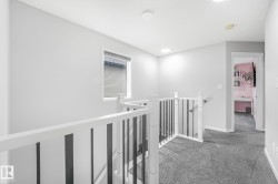 Upper-level landing featuring light gray walls and dark gray carpeting - 