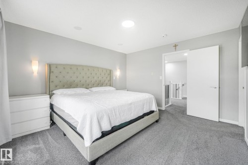 Carpeted bedroom with light gray walls, featuring a circular ceiling light and two wall sconces - 17724 58 Street Nw, Edmonton, AB 
