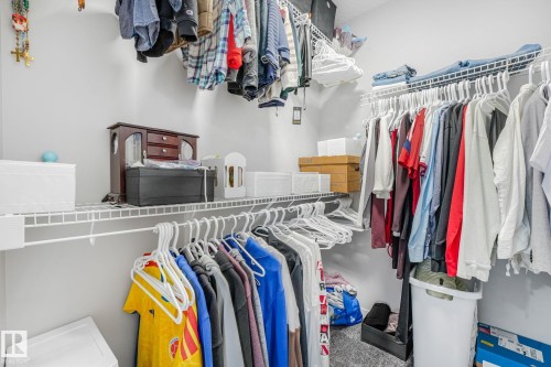Walk-in closet featuring white wire shelving, multiple hanging rods, and light gray walls - 17724 58 Street Nw, Edmonton, AB 