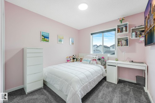 Bedroom featuring plush gray carpeting, a large window, and built-in floating shelves - 17724 58 Street Nw, Edmonton, AB 