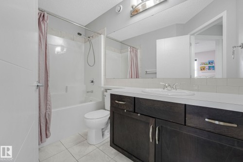 Contemporary bathroom featuring a dark wood-finish vanity with an integrated sink, a white subway tile backsplash, and a large wall-mounted mirror - 17724 58 Street Nw, Edmonton, AB 
