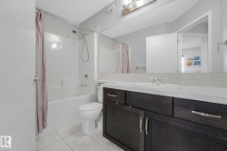 Contemporary bathroom featuring a dark wood-finish vanity with an integrated sink, a white subway tile backsplash, and a large wall-mounted mirror - 