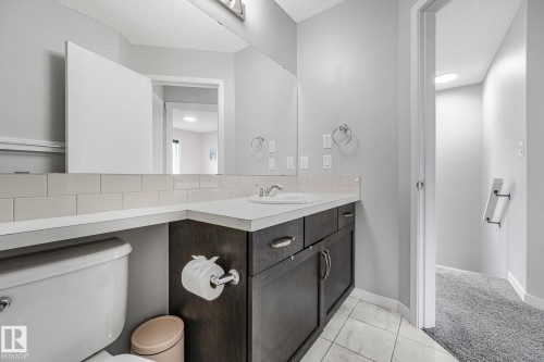 Bathroom featuring a single-sink vanity with dark wood-finish cabinetry, light-toned countertop, and subway tile backsplash - 17724 58 Street Nw, Edmonton, AB 