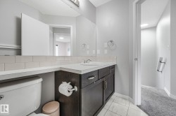 Bathroom featuring a single-sink vanity with dark wood-finish cabinetry, light-toned countertop, and subway tile backsplash - 