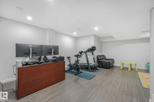Spacious room featuring light gray walls, recessed lighting, and wood-finish flooring - 17724 58 Street Nw, Edmonton, AB 