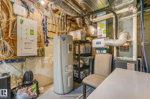 Utility room featuring an electrical panel, water heater, and forced-air furnace - 17724 58 Street Nw, Edmonton, AB 