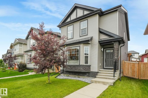 Two-story residence featuring light gray siding, dark trim accents, a prominent bay window, and a dark front door - 17724 58 Street Nw, Edmonton, AB 