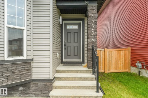 Concrete front steps with a dark gray entry door, complemented by light gray siding and dark stacked stone accents - 17724 58 Street Nw, Edmonton, AB 