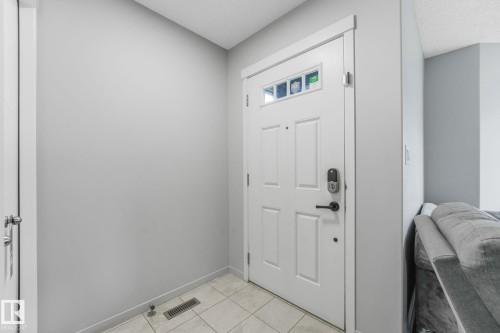 Entryway featuring a white paneled door with decorative glass inserts and a digital lock - 17724 58 Street Nw, Edmonton, AB 