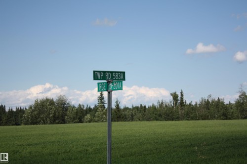 Expansive green field bordered by a dense tree line under a broad blue sky - Rr202 Twp583, Rural Thorhild County, AB 