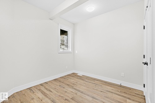 Room featuring wood-finish flooring, white baseboards, and a single window with white trim - 204 Falcon Crescent, Leduc, AB 