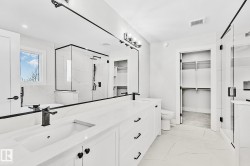 Spacious bathroom with a dual vanity featuring stone countertops and integrated sinks - 