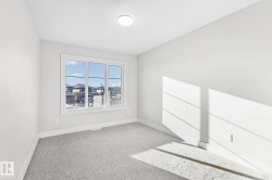 Bright room featuring a large window, soft gray carpeting, white baseboards, and a flush-mount ceiling light - 
