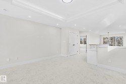 Spacious interior room featuring light-toned carpeting and a tray ceiling with recessed lighting - 