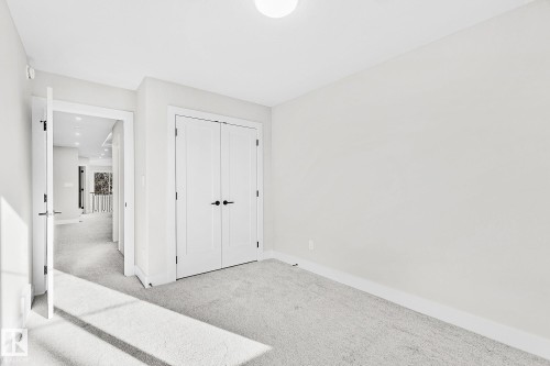 Carpeted room with white walls, a flush-mount ceiling light, and white baseboards - 204 Falcon Crescent, Leduc, AB 