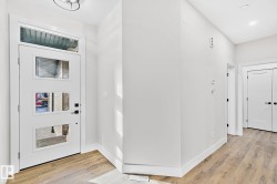 Foyer featuring a contemporary white entry door with frosted glass panels, a transom window, and a modern ceiling light fixture - 