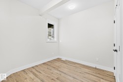 Room featuring wood-finish flooring, white baseboards, and a single window with white trim - 